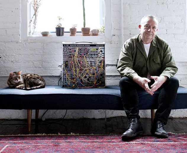 Drew McDowall seated beside a modular synthesiser
